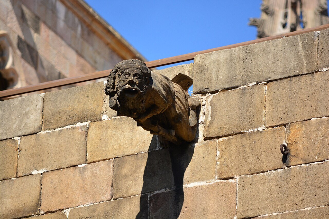 A weathered stone gargoyle projecting from a wall of Barcelona Cathedral.
