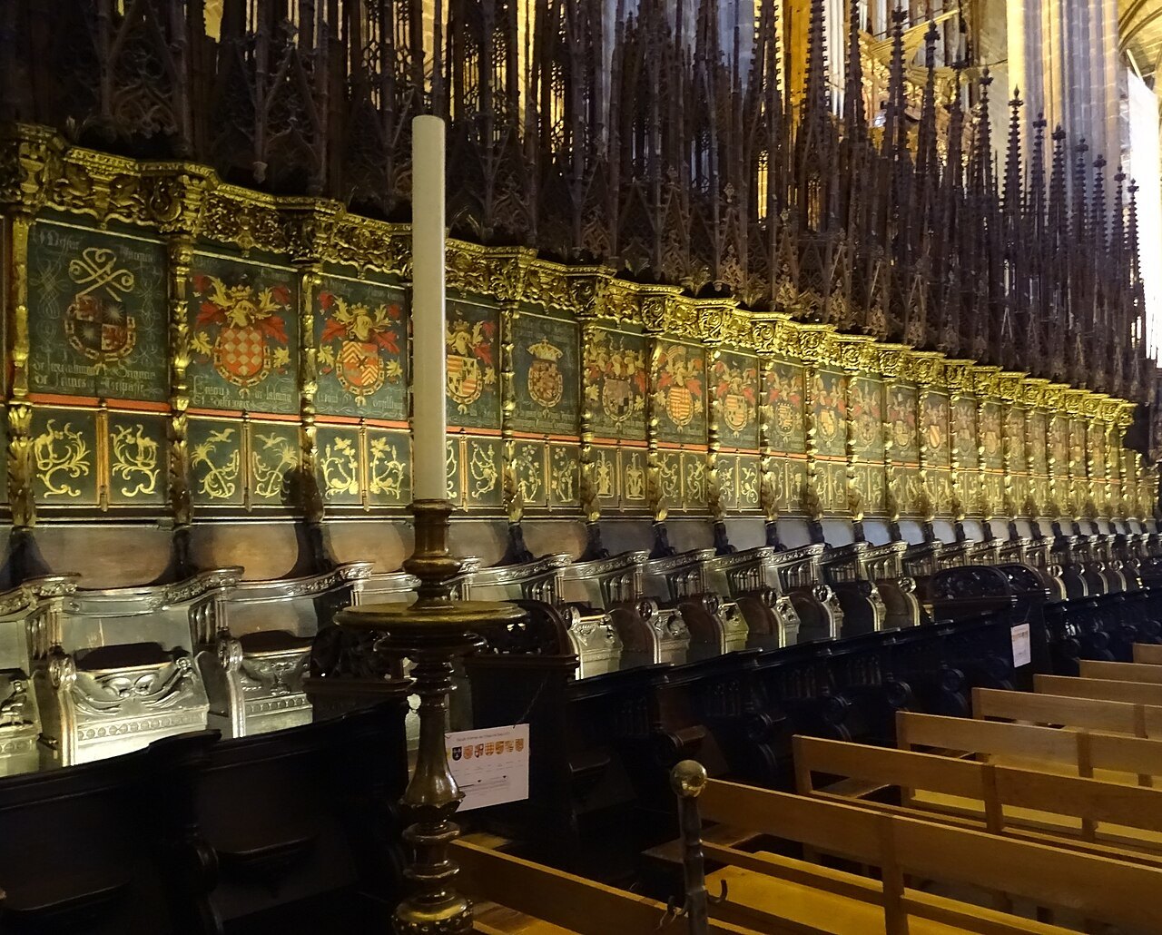The carved choir stalls, with a tall candle standing in the aisle.