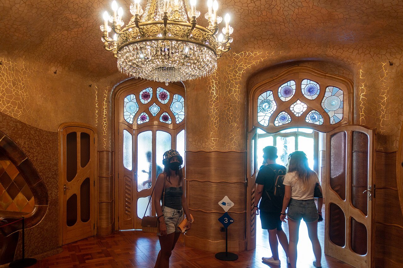 Visitors in the chandelier-lit main salon of Casa Batlló, with its stained-glass windows.