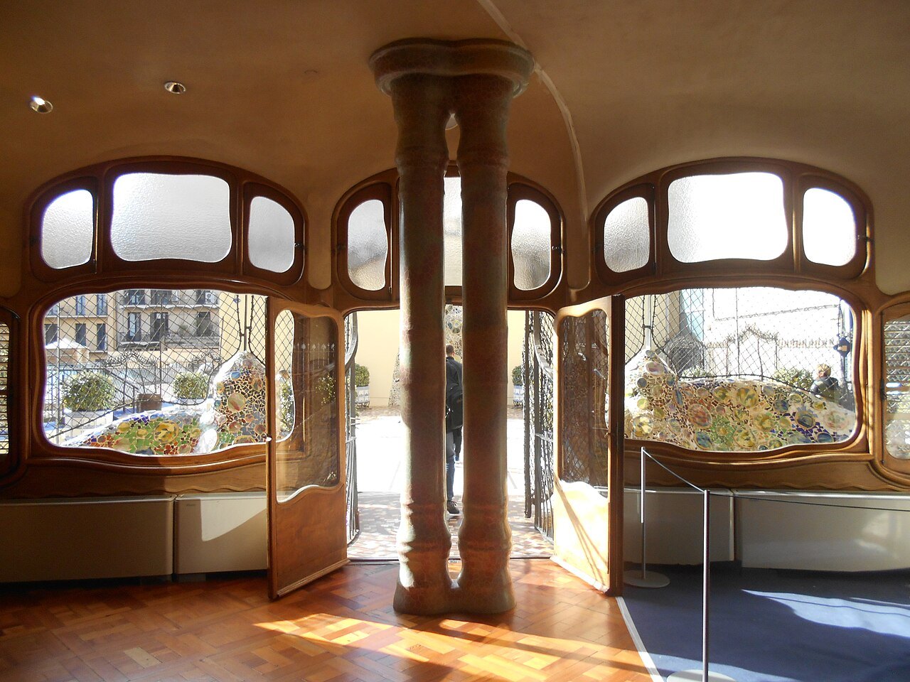 A room with round-topped windows, a slender central column and open glazed doors at Casa Batlló.