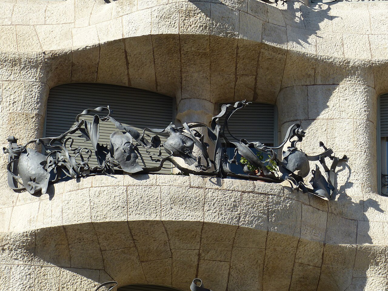 Twisting wrought iron on a balcony of Casa Milà's stone façade.