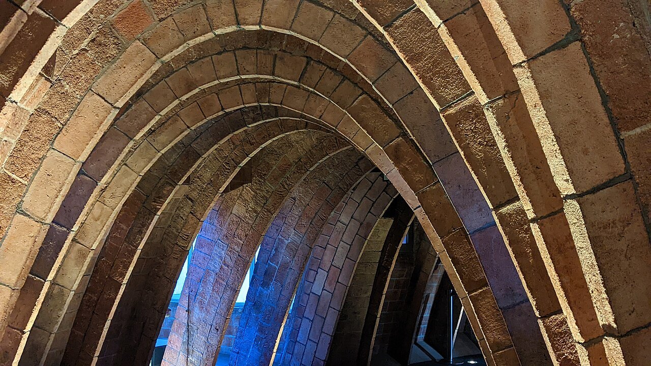 A brick-lined arch in the attic of Casa Milà, with blue light beyond it.