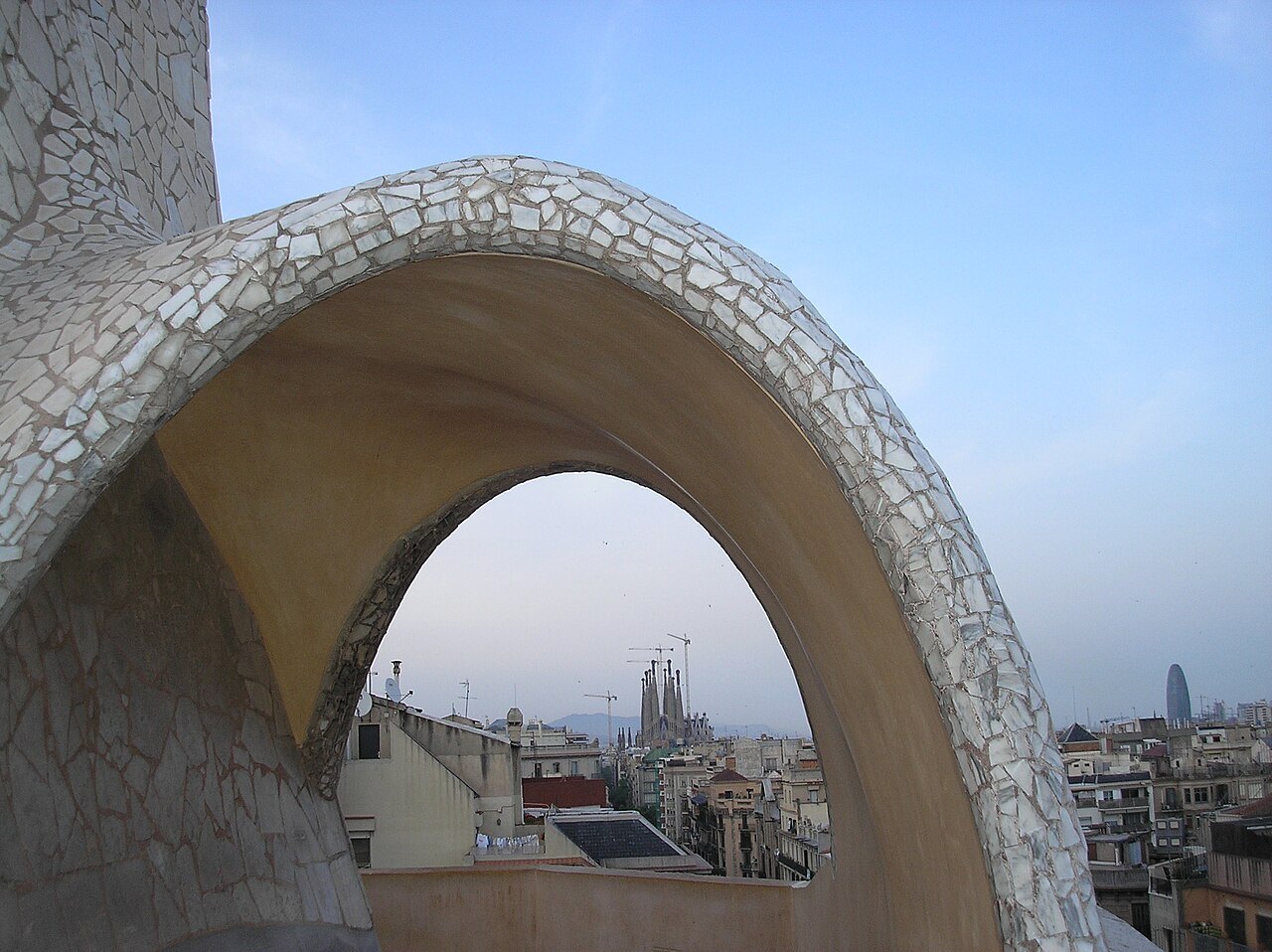 A tiled arch on Casa Milà's roof framing the city beyond.
