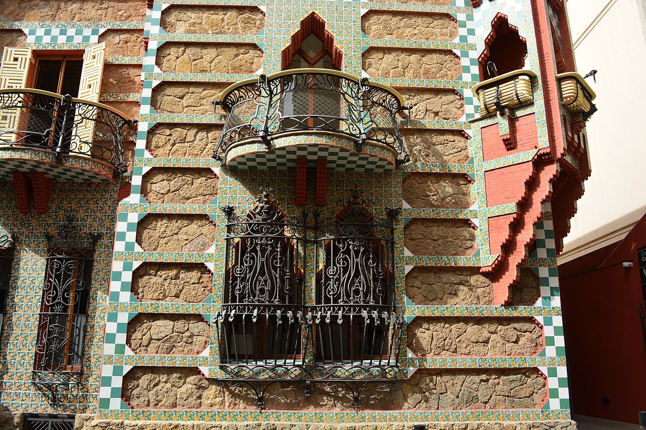 The tiled and brick façade of Casa Vicens with a balcony and iron-grilled windows.