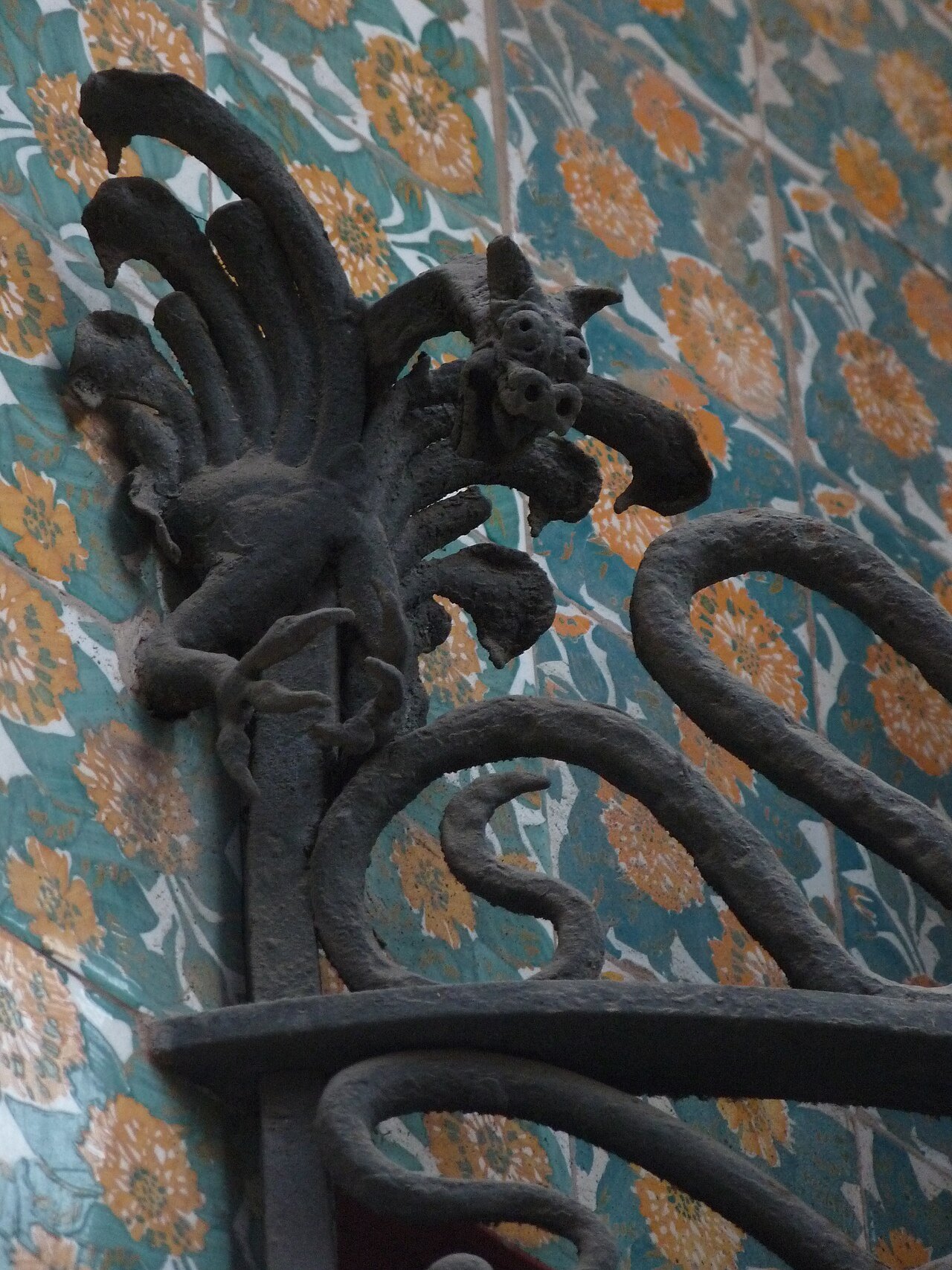 A wrought-iron dragon against a wall of flower-patterned tile at Casa Vicens.