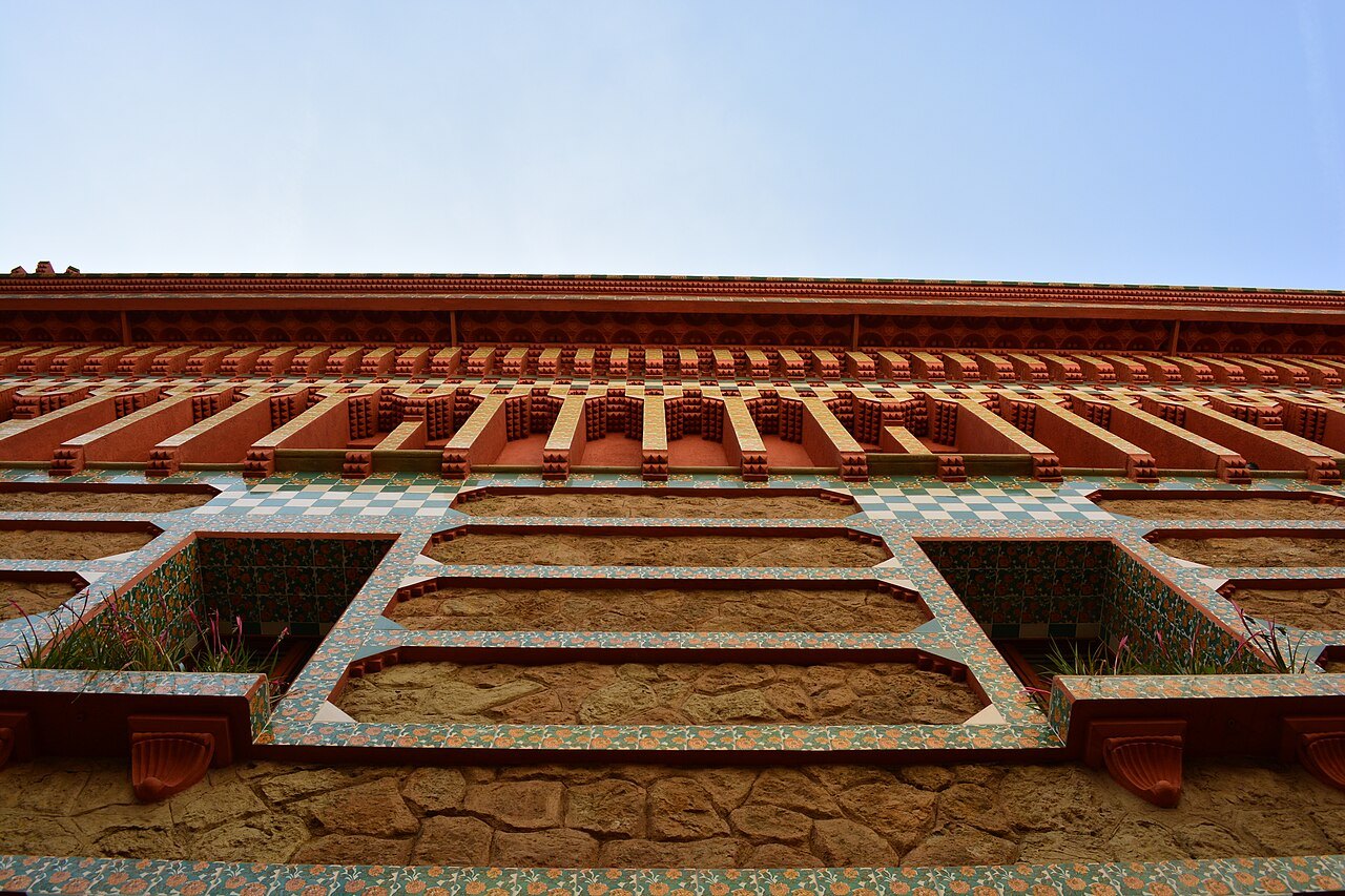 The stepped red cornice and brick of Casa Vicens against the sky.