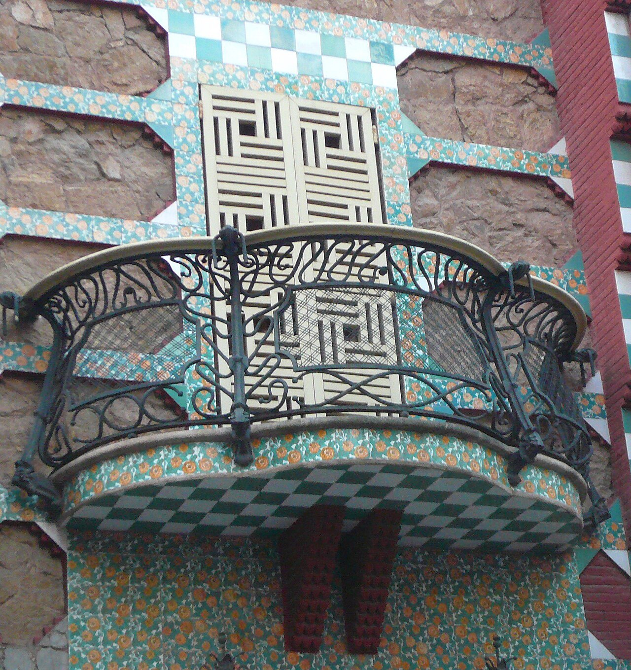 A balcony of curling ironwork against the tiled wall of Casa Vicens.