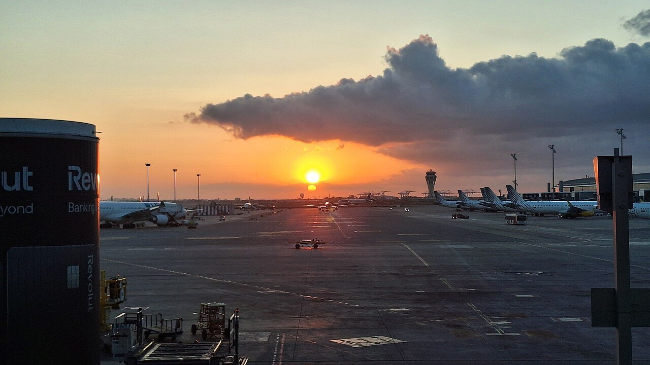 The sun setting behind a bank of cloud over the aircraft stands at Barcelona airport.
