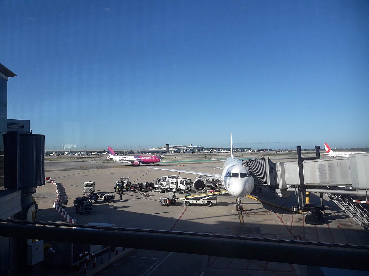An aircraft at its stand beyond the terminal glass at Barcelona airport.