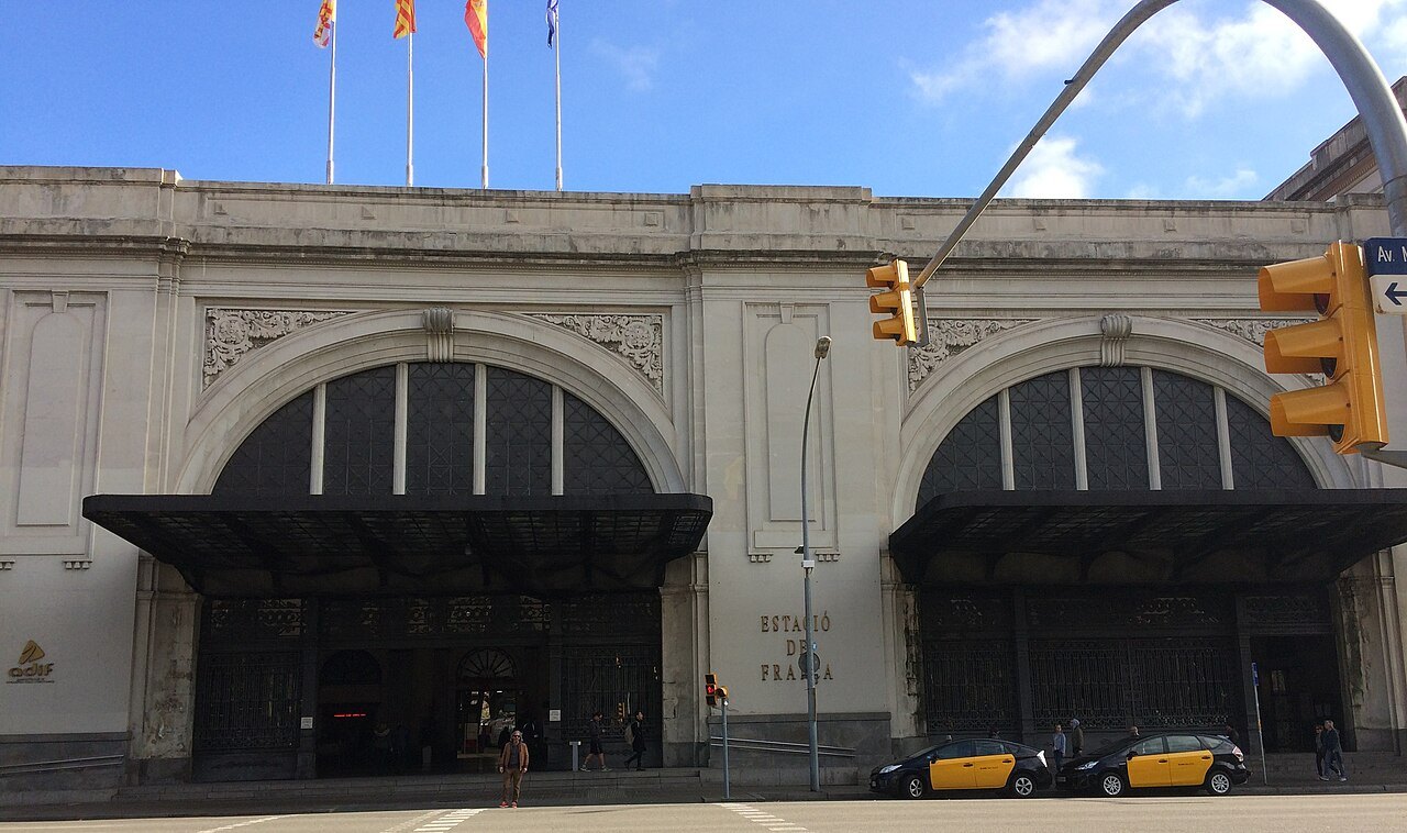 The front of Estació de França, two large arched openings under a row of flags.