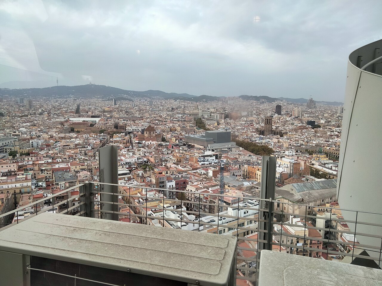 Rooftops of the city stretching to the Collserola hills, seen from a high tower.