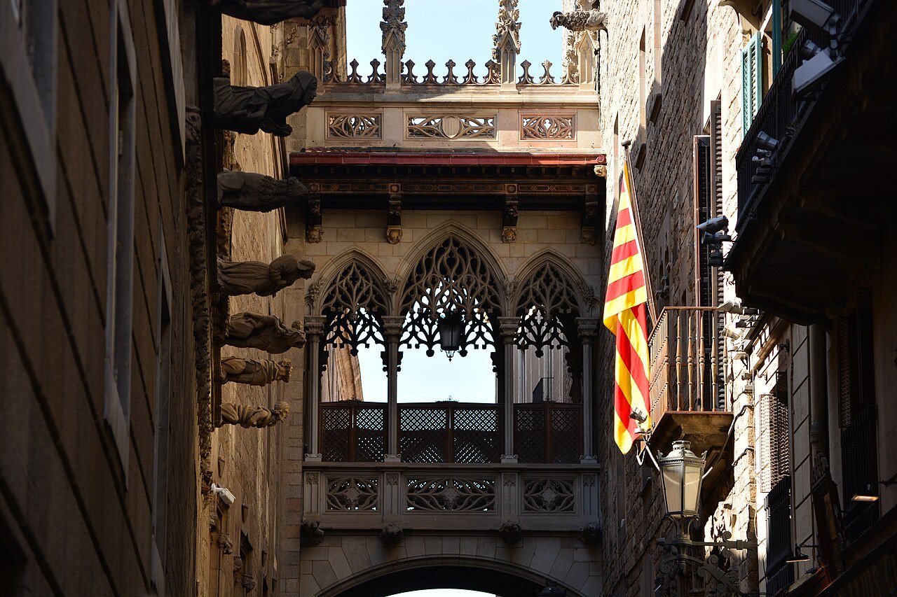 The Gothic Revival bridge over Carrer del Bisbe, with a Catalan flag hanging beside it.