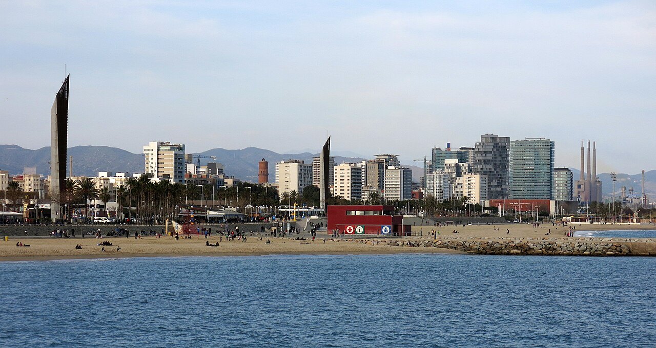The Nova Icària and Bogatell beaches seen from the water, with tall buildings behind the sand.