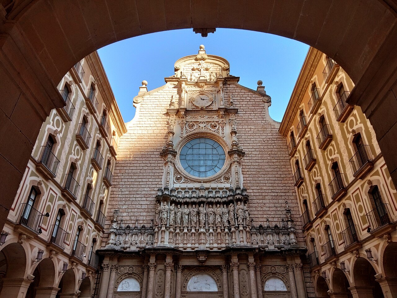 The basilica façade at Montserrat, framed through an arched passage.