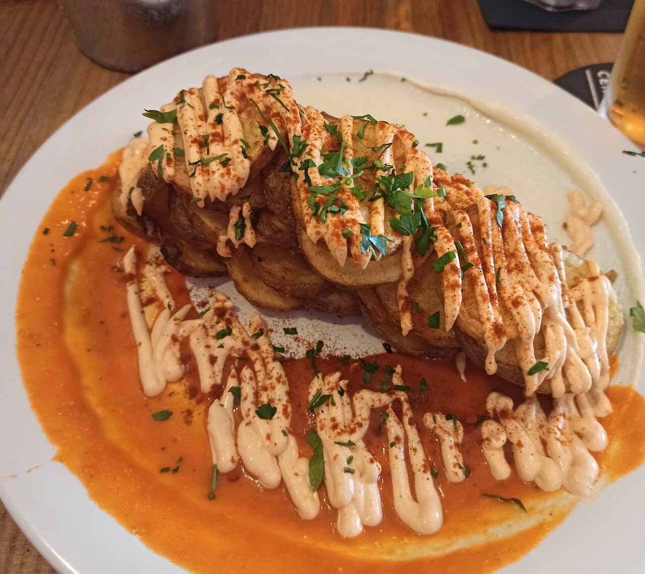 Fried potatoes under a red sauce and a drizzle of aioli.