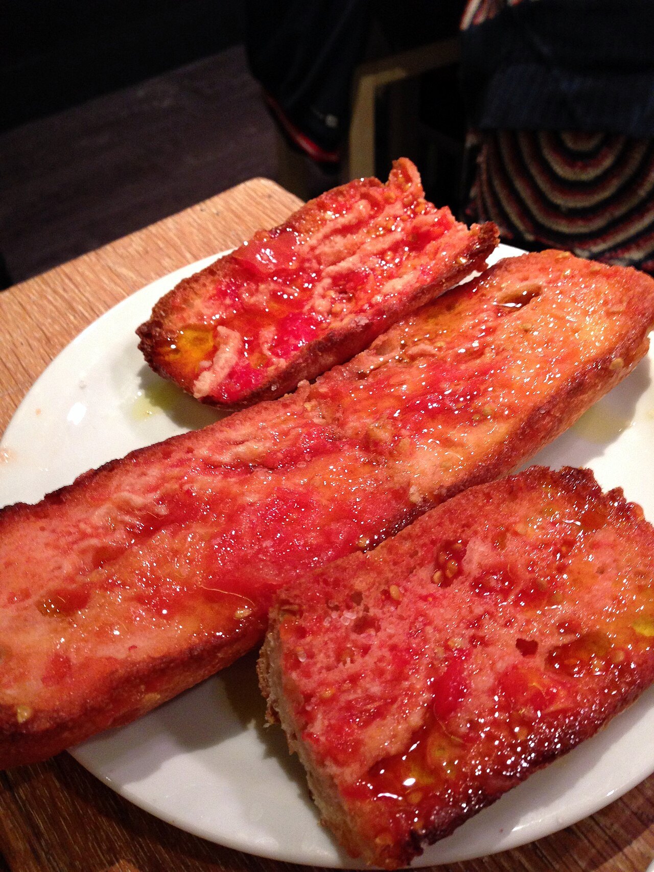 Toasted bread rubbed with tomato, served on a plate.
