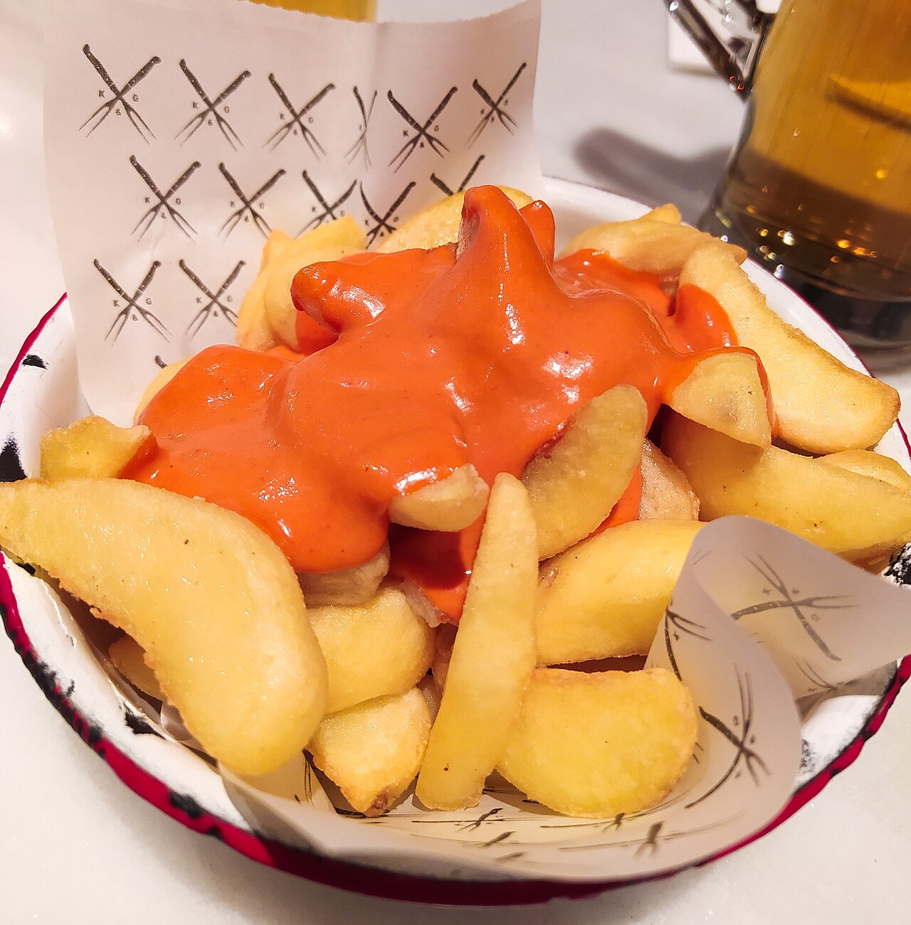 A basket of fried potatoes under an orange sauce.