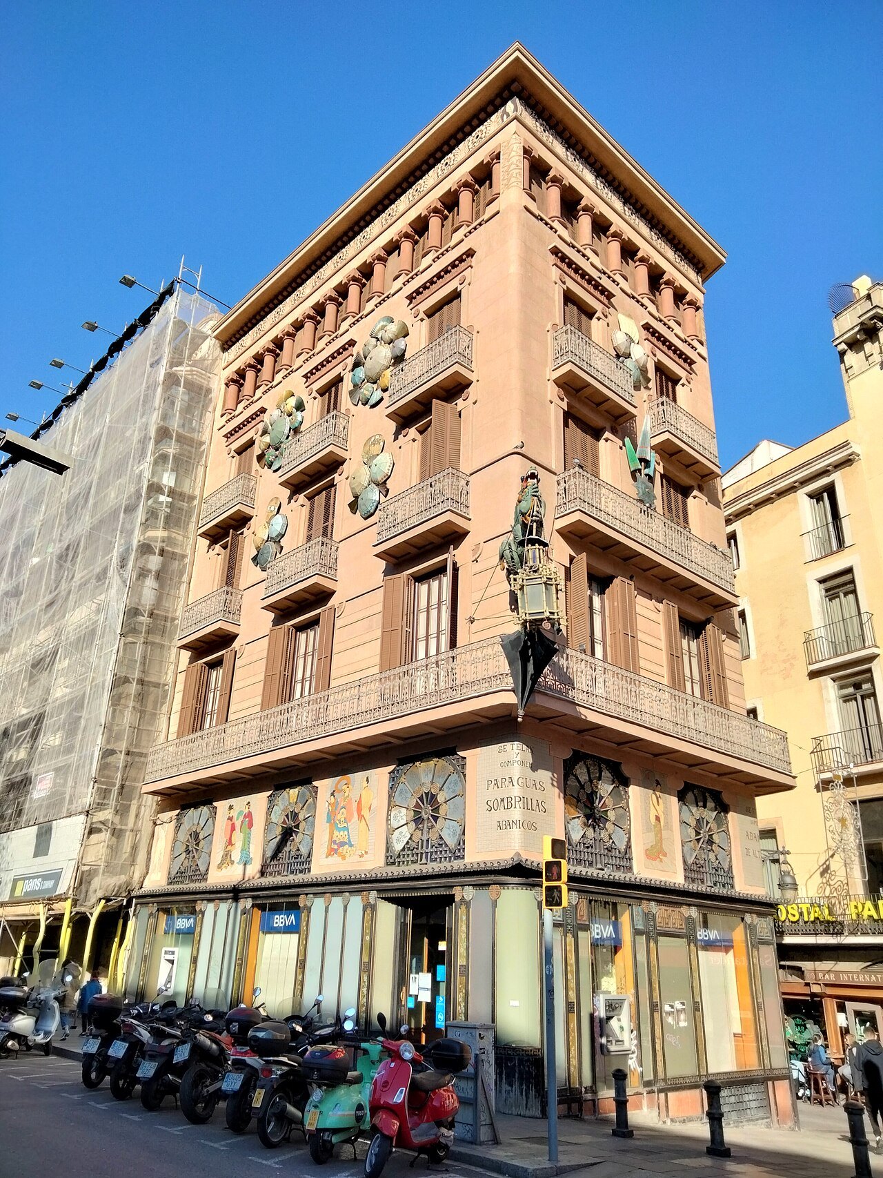 A decorated corner building on the Rambla, with scooters parked at its foot.