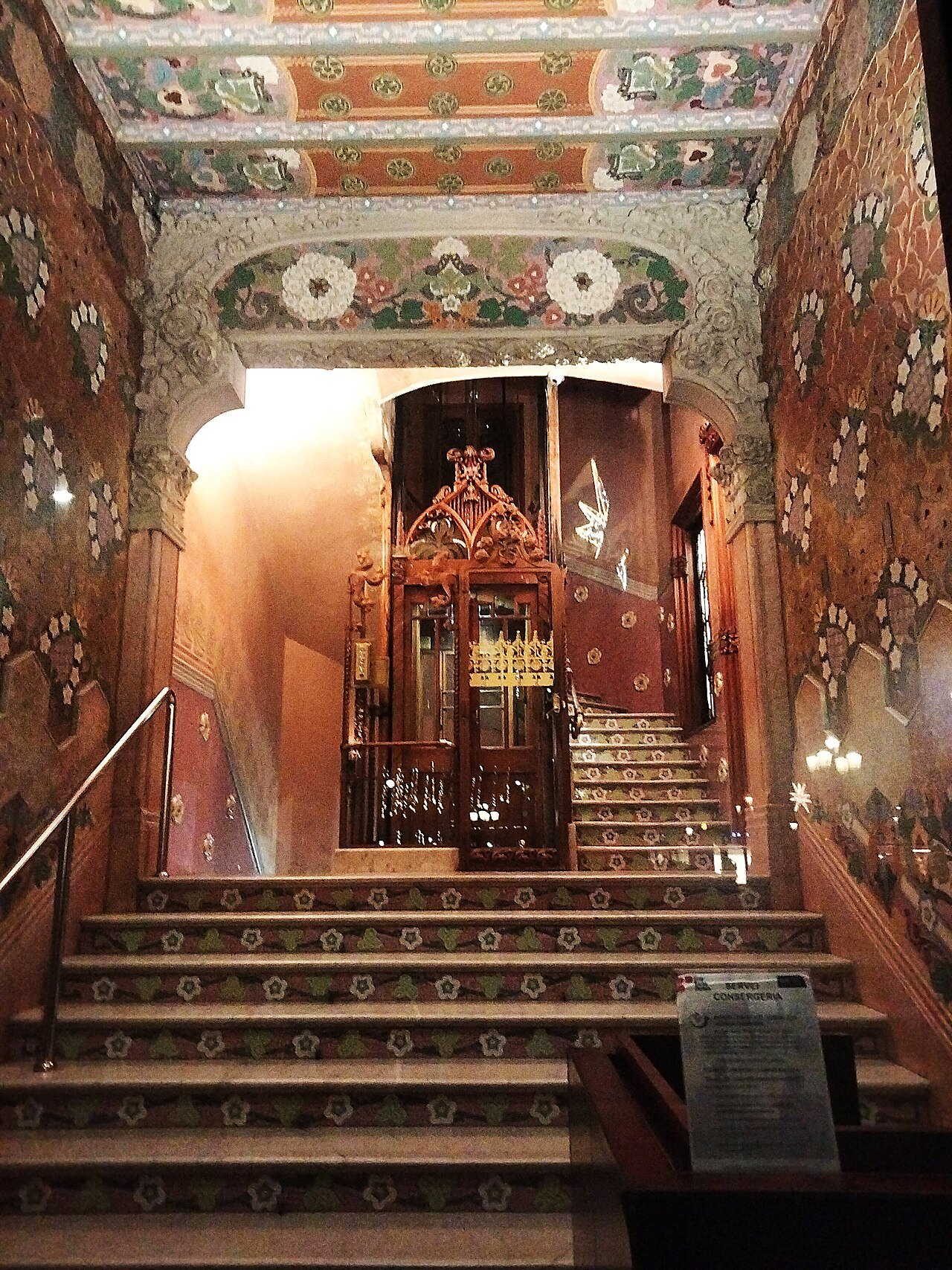 The richly decorated stair hall of Casa Lleó Morera, lit in warm light.