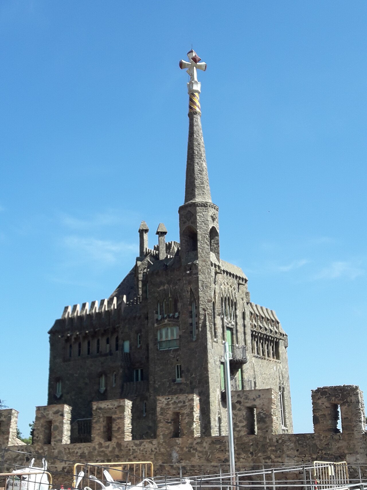 The castle-like tower of Bellesguard, topped by a cross, over a crenellated wall.