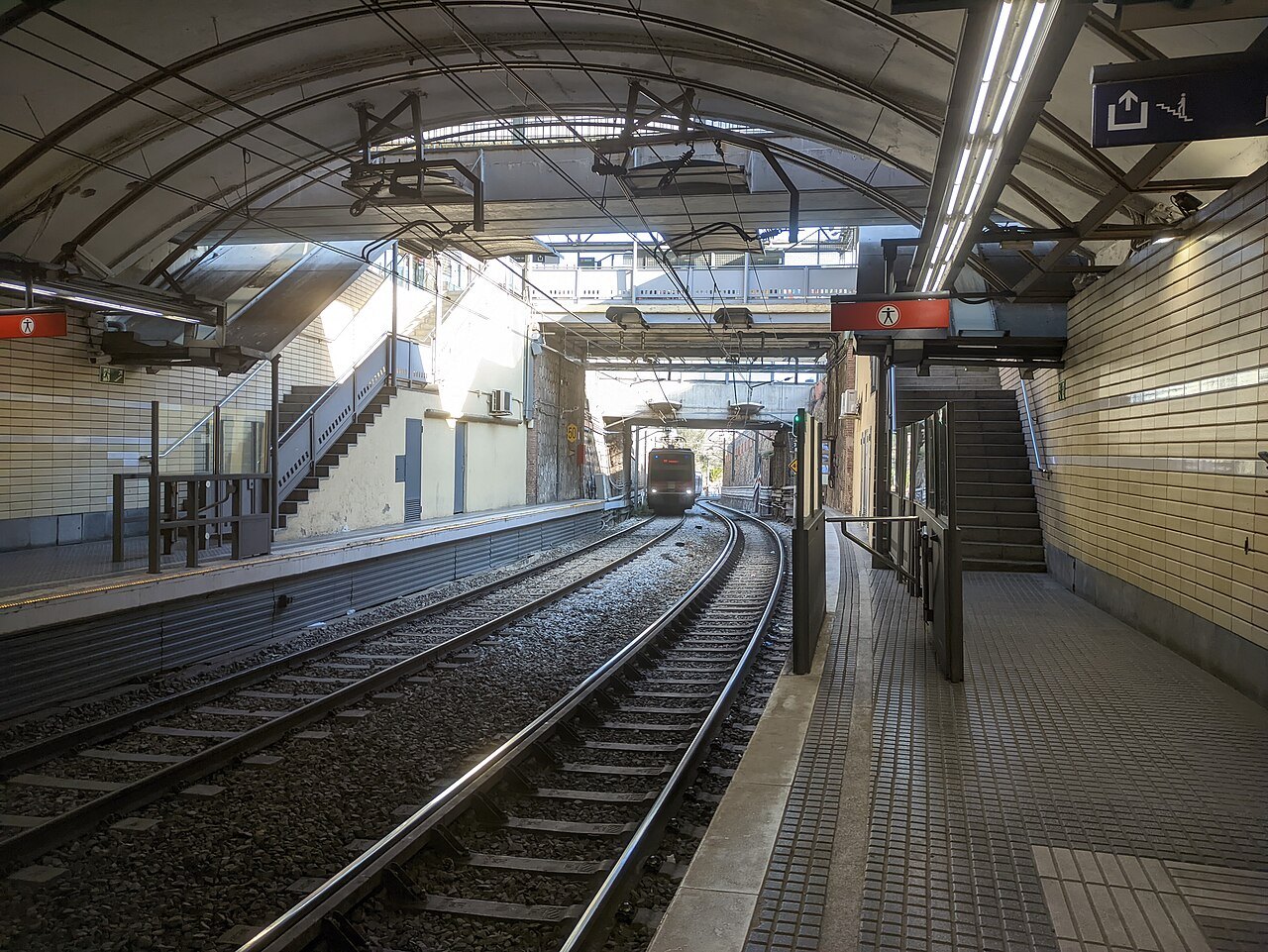 A train approaching the platform at Peu del Funicular station, in daylight.