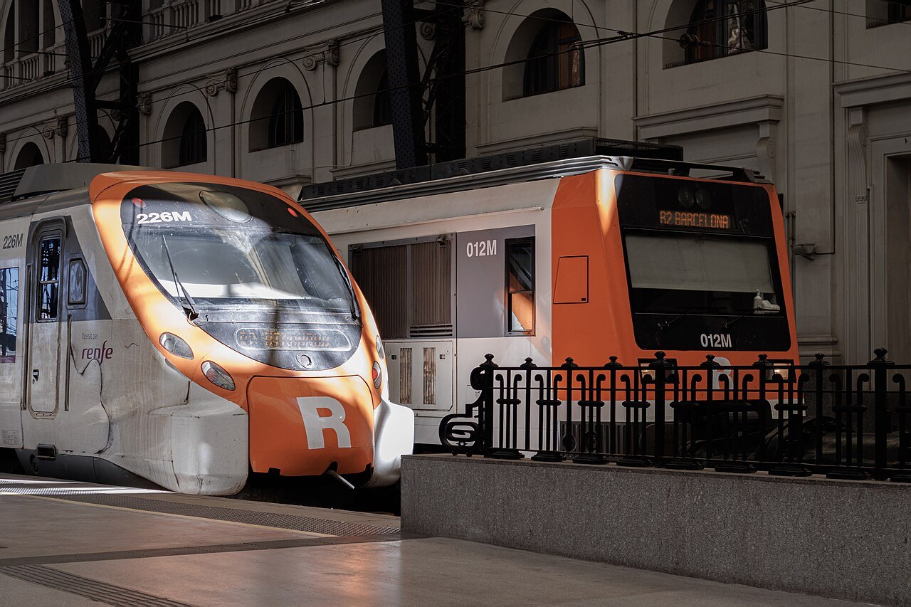 An orange-and-white Rodalies commuter train at a platform of Estació de França.