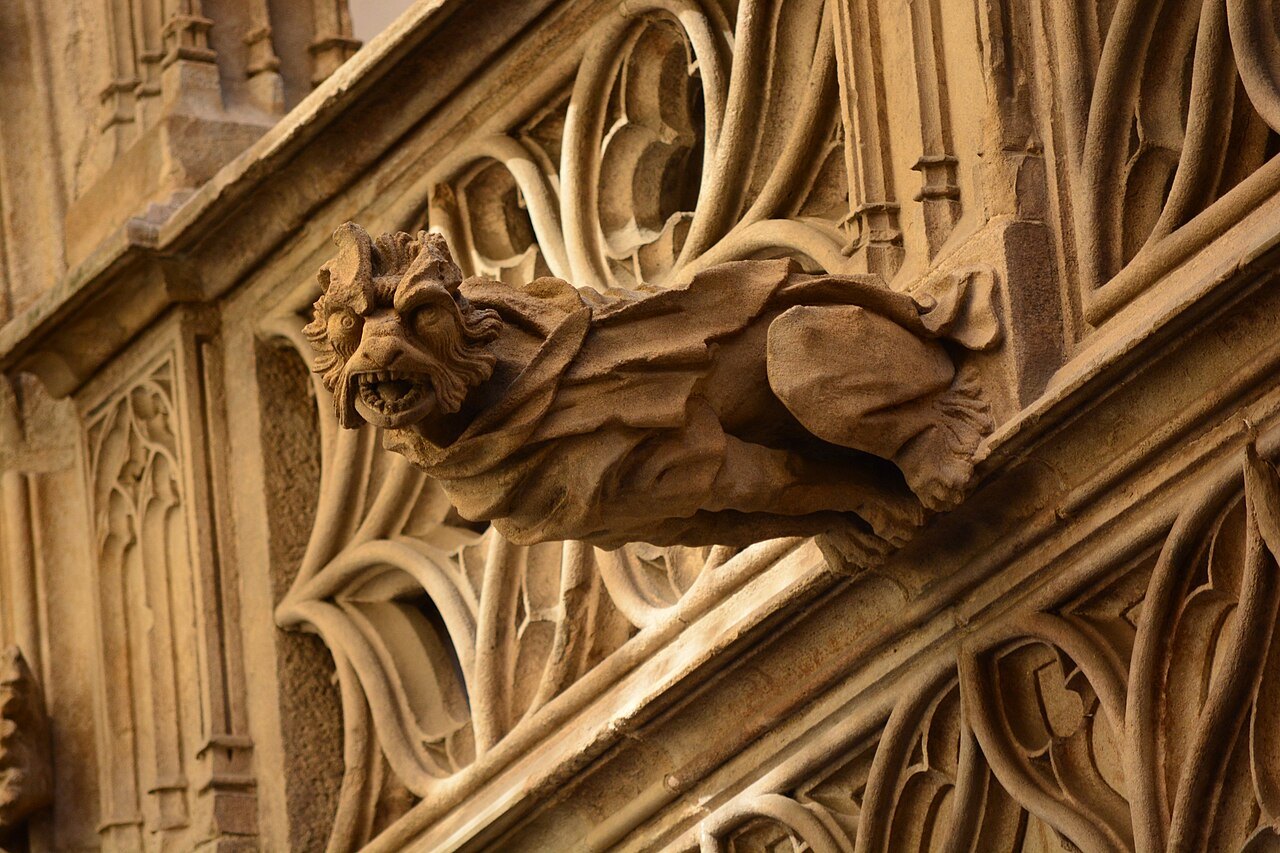 A stone gargoyle among Gothic tracery on the Palau de la Generalitat.