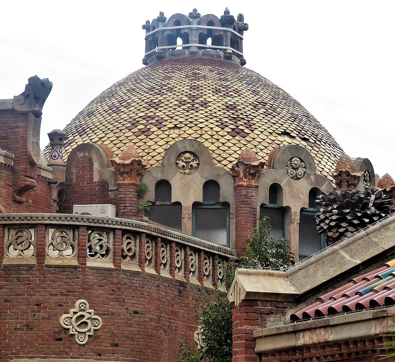 A tiled dome above brick walls with carved ornament at Sant Pau.