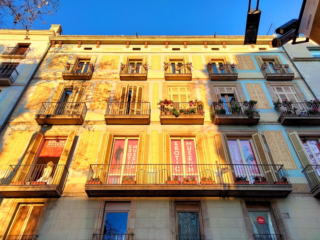A warmly lit apartment building on the Rambla, its balconies on every floor.