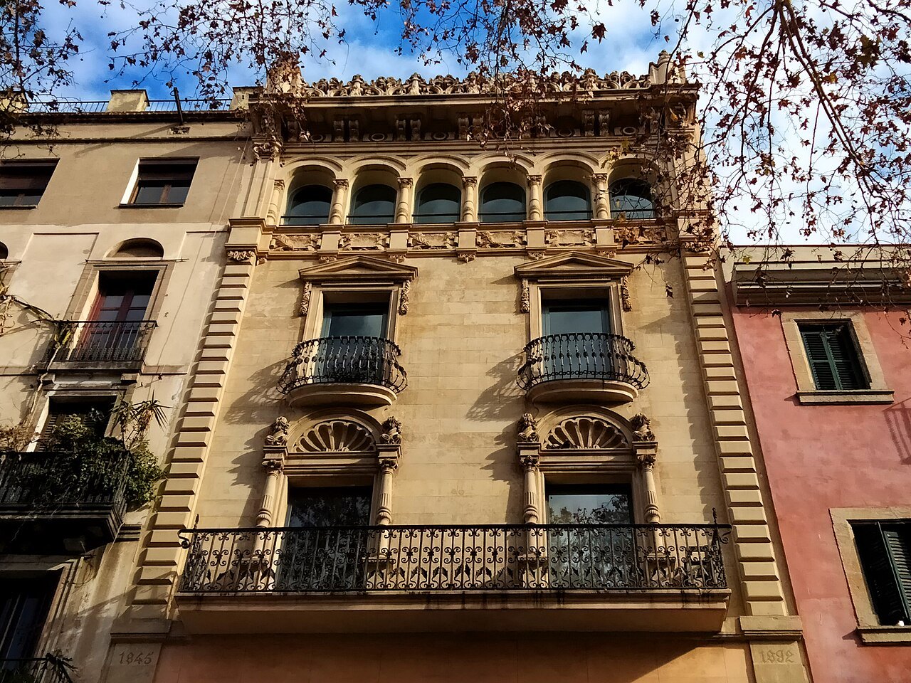 An arcaded, balconied building at Rambla 18, in warm stone.