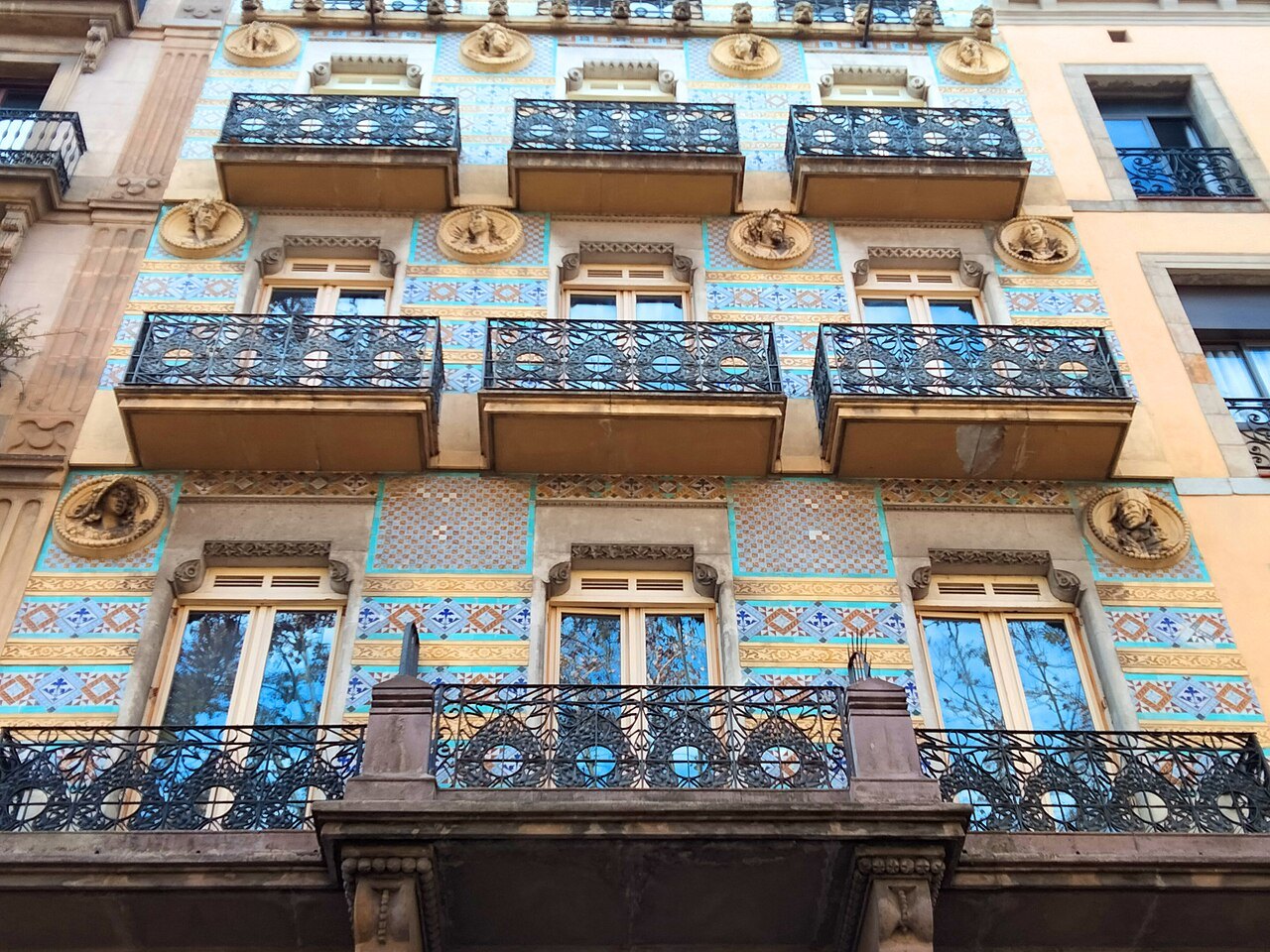 A building on the Rambla with blue-tiled balconies and ironwork railings.