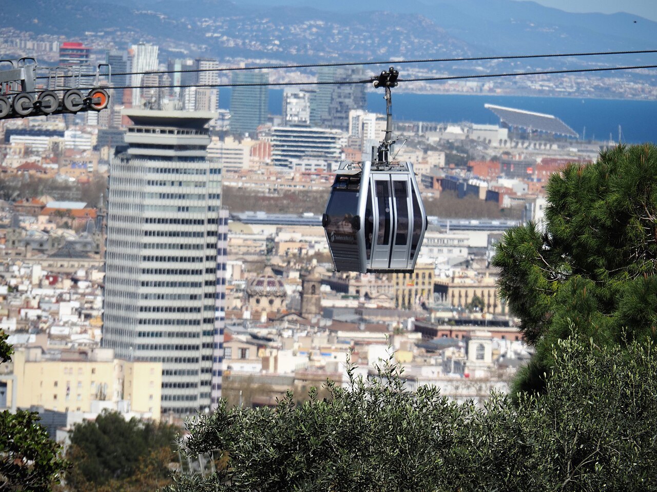 A cable-car gondola on its wire above the rooftops and a tower block.
