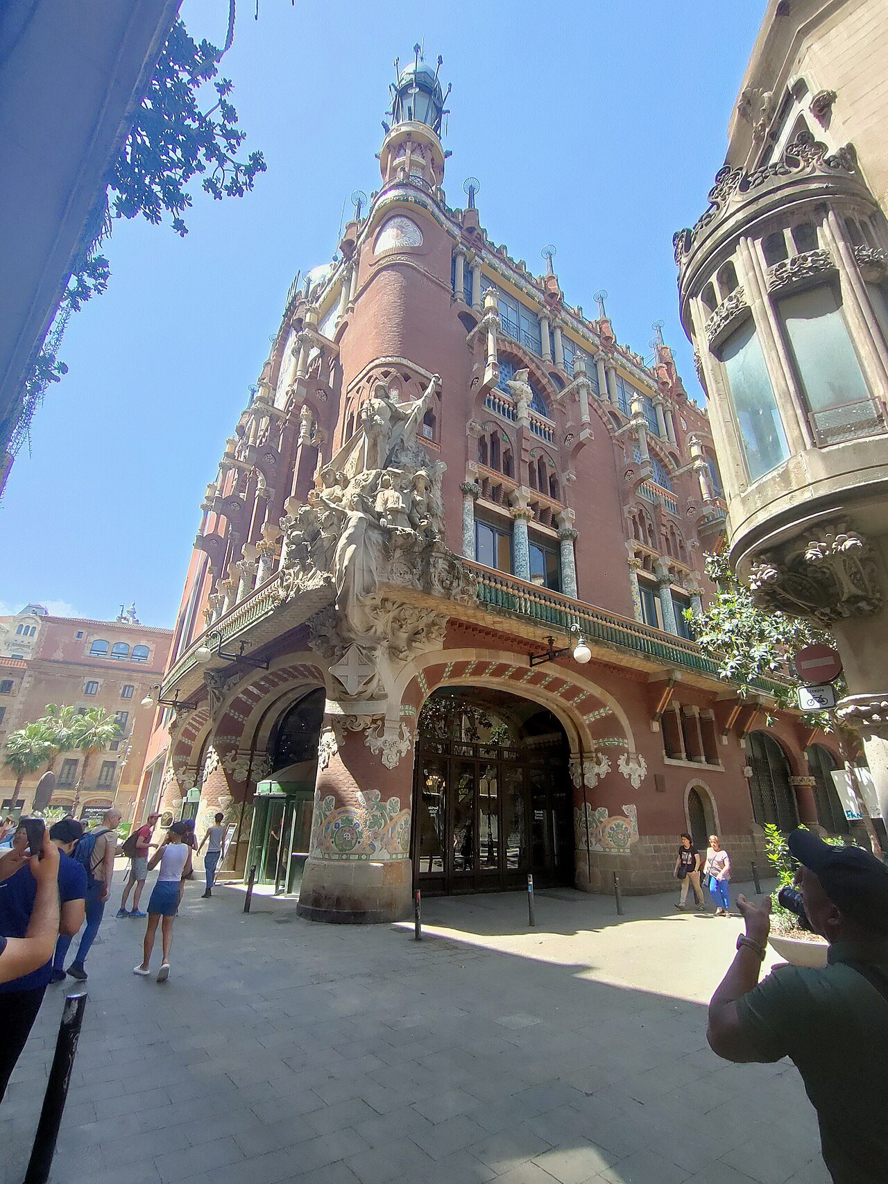 The Palau's corner from the street, a few passers-by in front of its arched entrances.