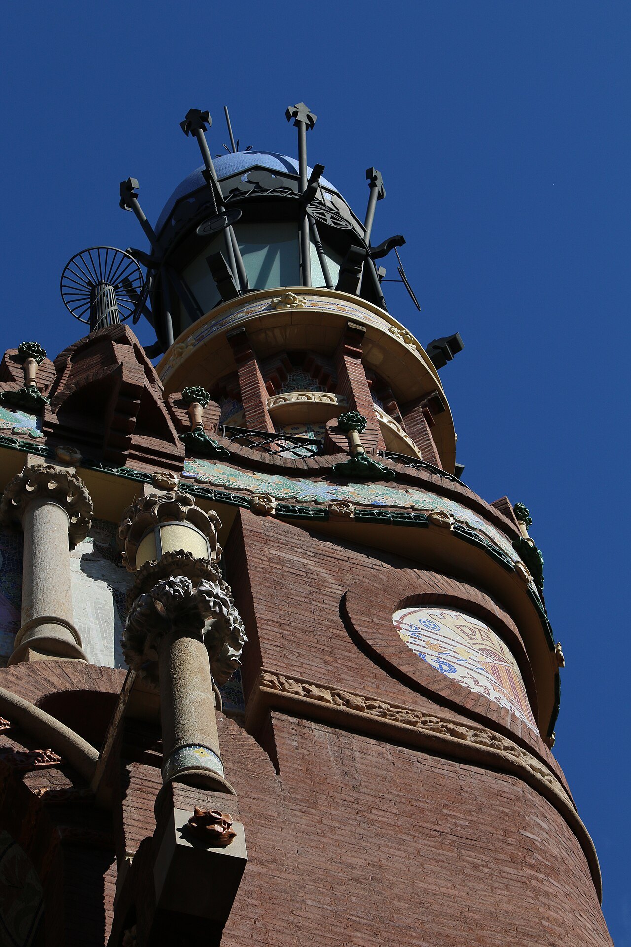 A turret with a lantern on top of the Palau de la Música, against a blue sky.