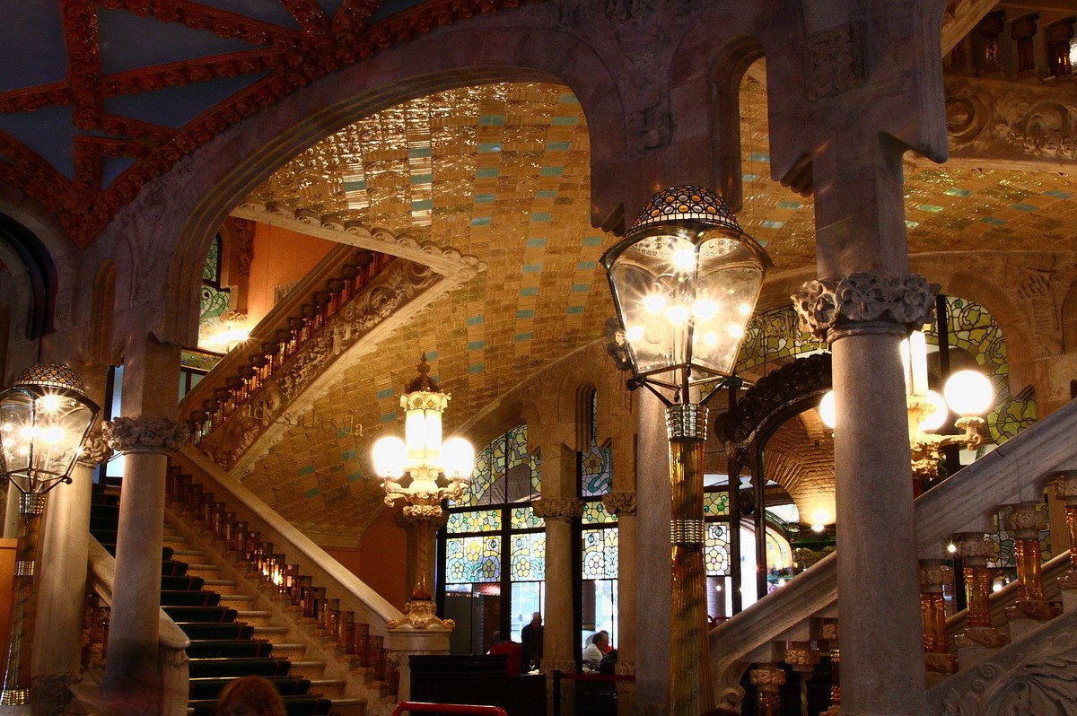 The staircase hall of the Palau de la Música, with lamps and a tiled vault.