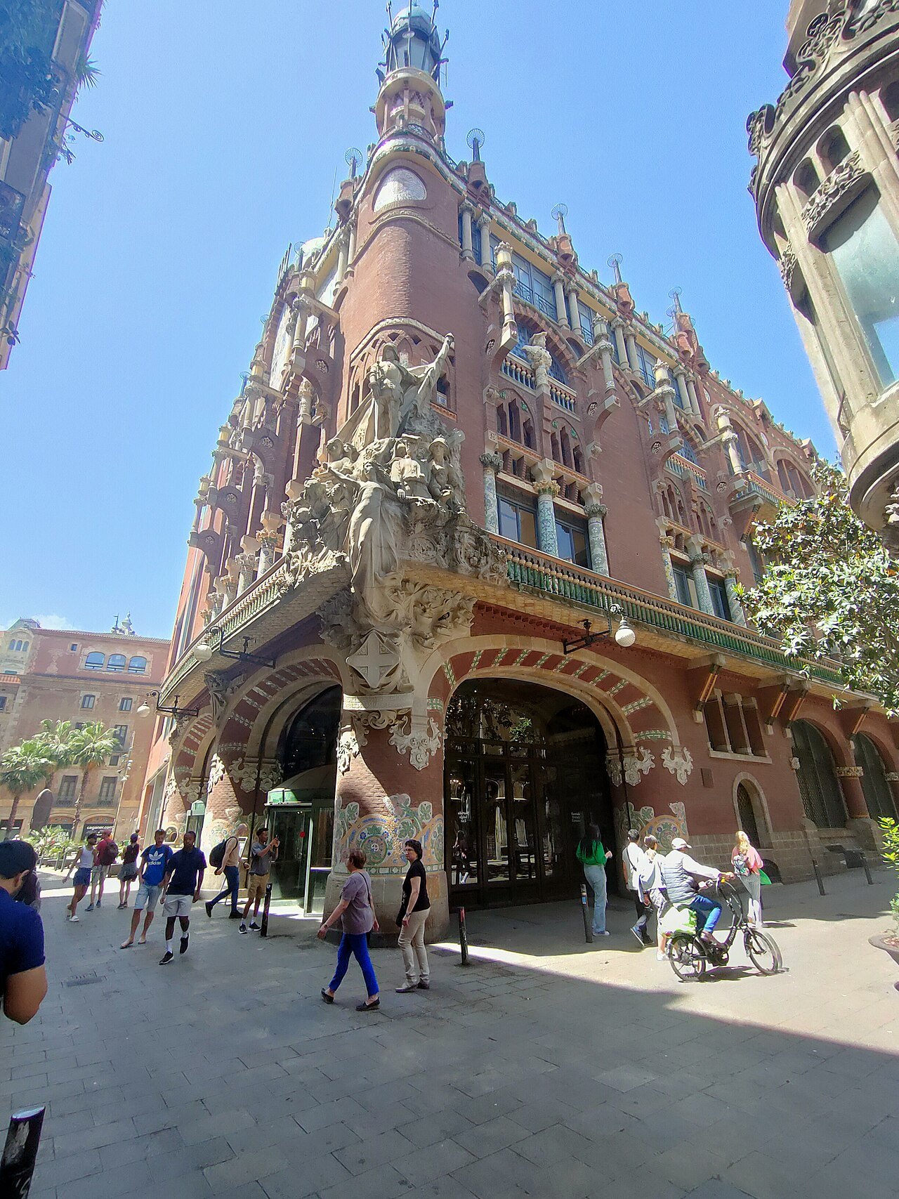 The corner of the Palau at street level, with people walking under the arches.