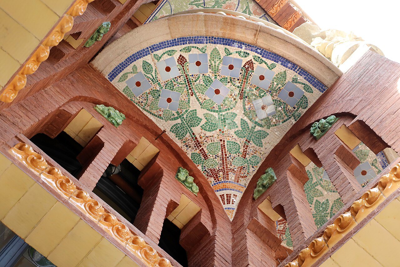 A tiled ceiling with a floral mosaic in a corner of the Palau de la Música.