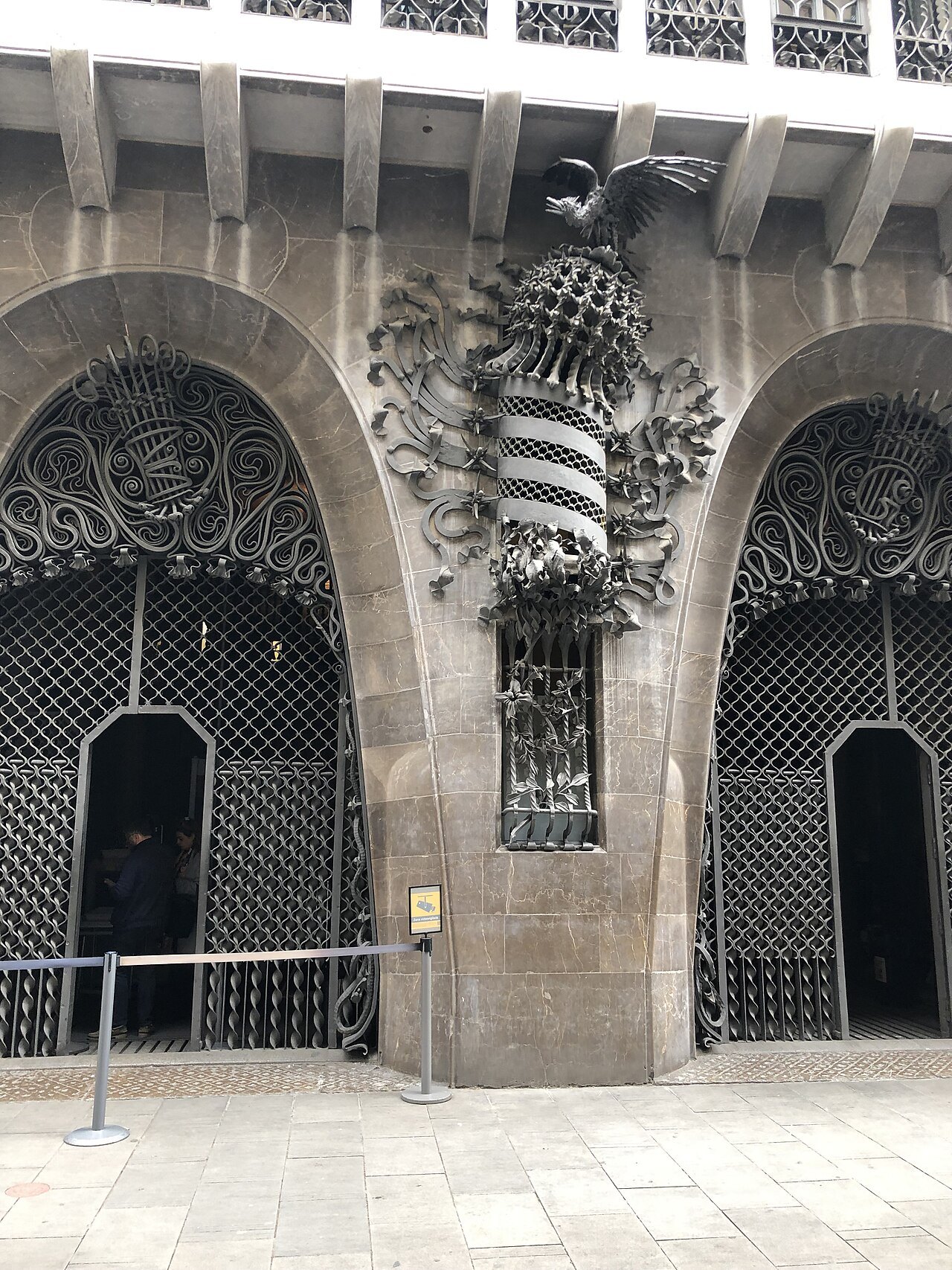 The two arched doorways of the Palau Güell, with a carved crest between them.