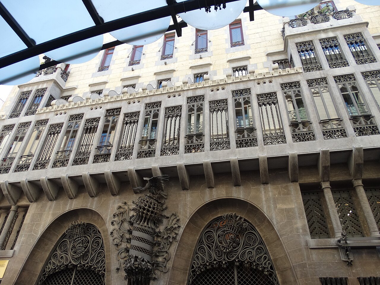 The façade of the Palau Güell, with arched doorways under a carved stone gallery.
