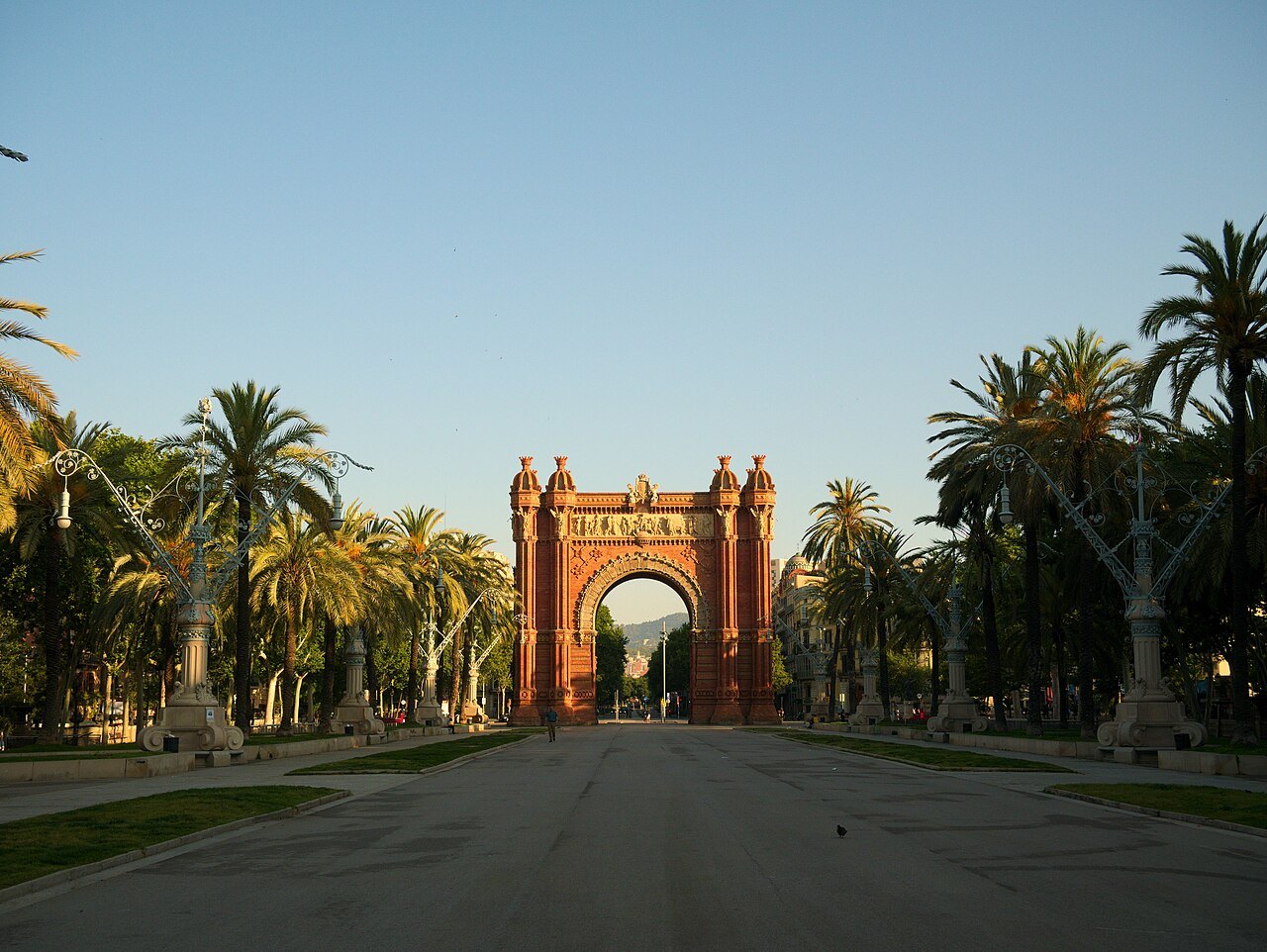 The Arc de Triomf seen along its avenue, with palm trees on both sides.