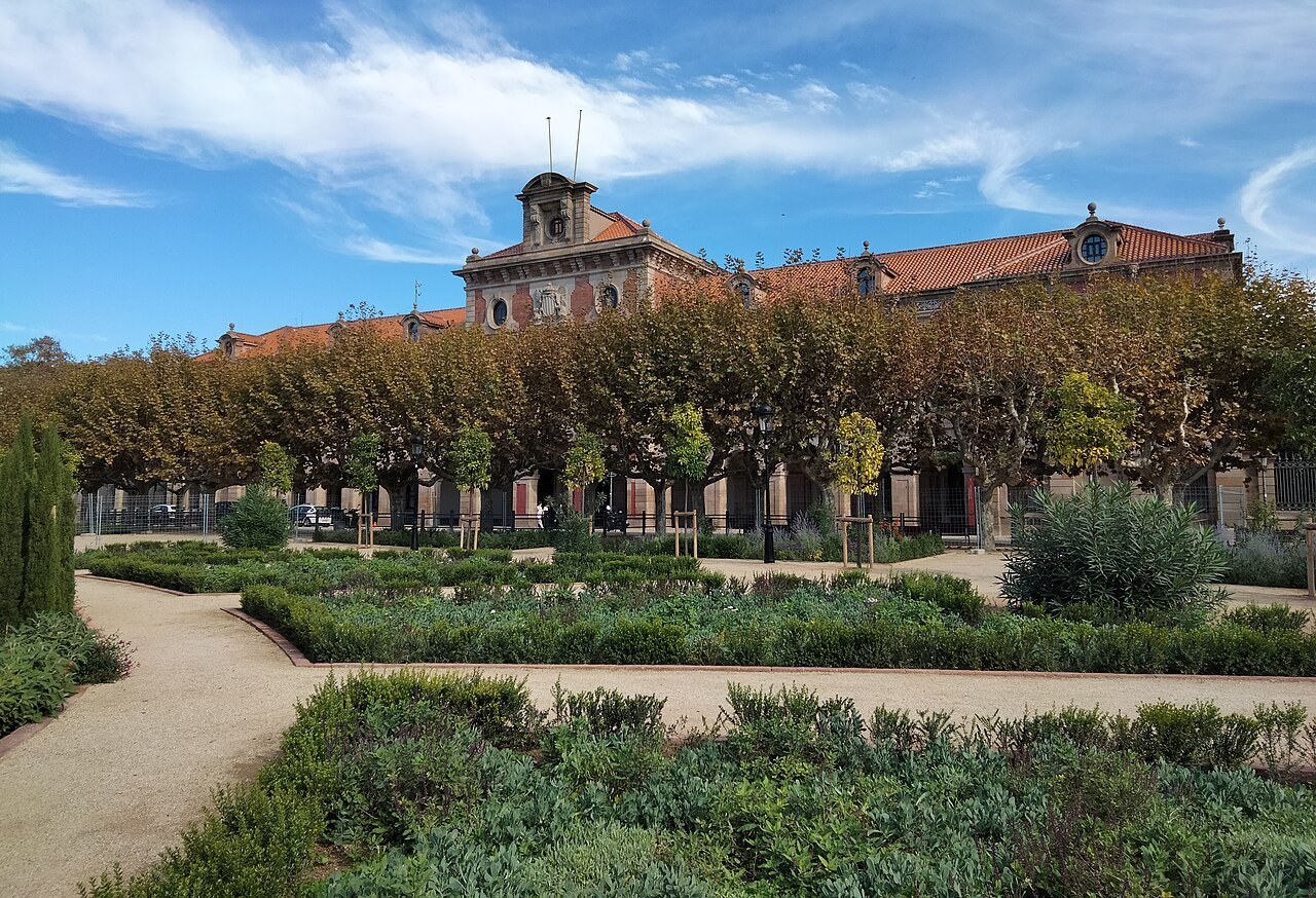 Clipped hedges and a curving path in front of the Parliament of Catalonia.