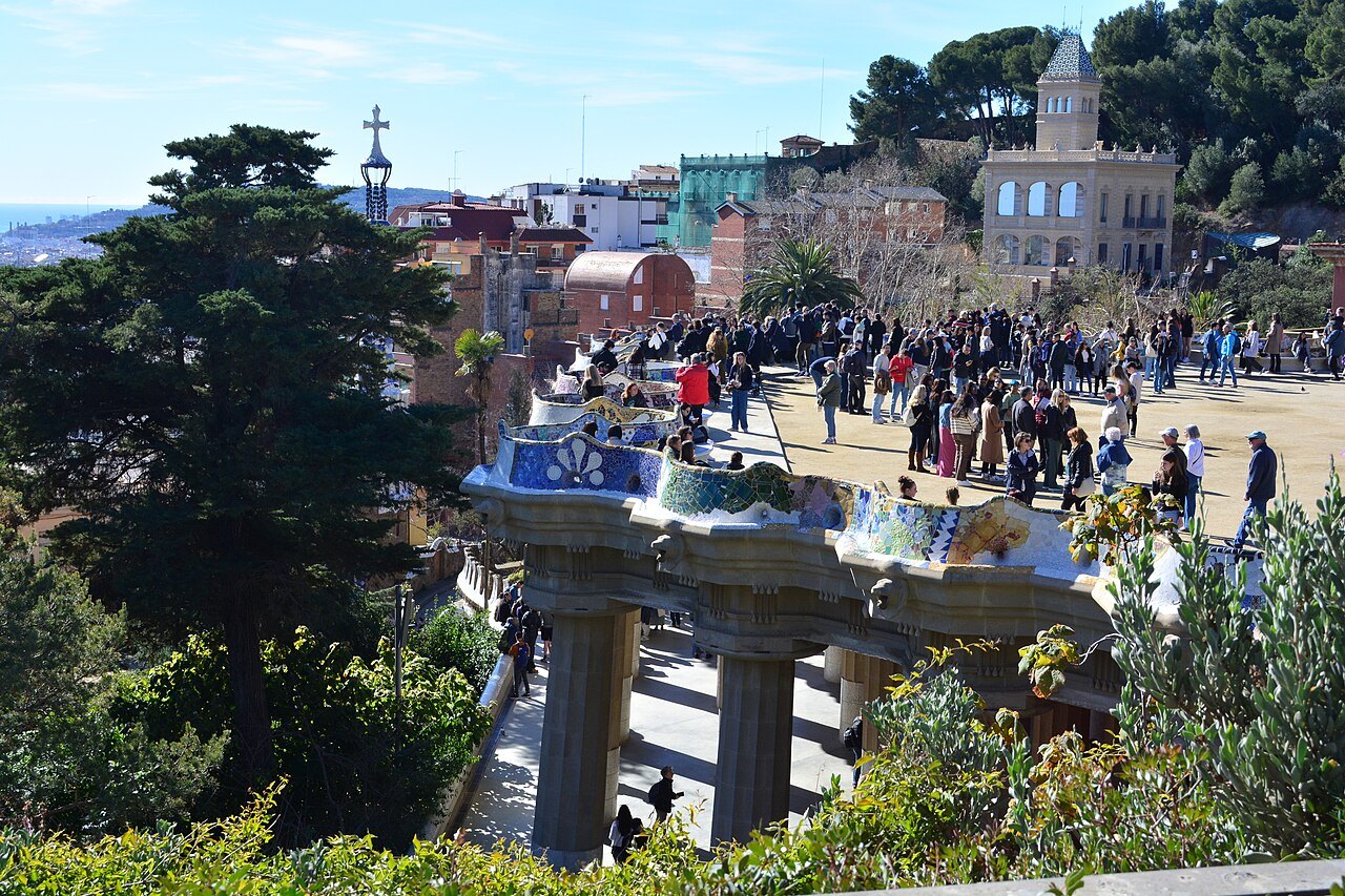 The main terrace of Park Güell seen from above, visitors crowded along the curve of its bench.