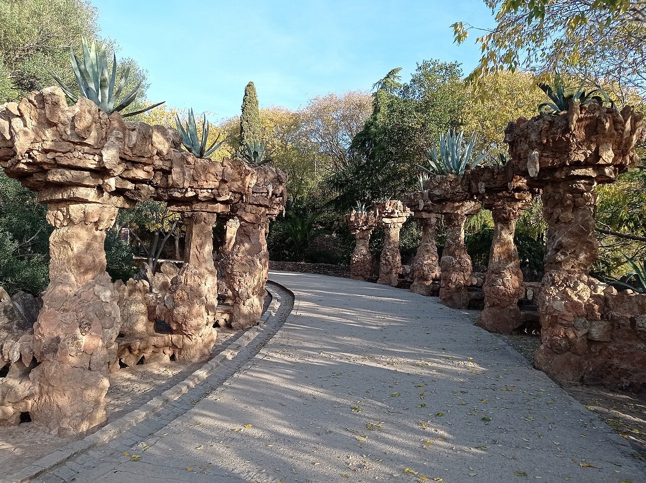 A path along one of Park Güell's viaducts, its stone columns leaning like tree trunks.