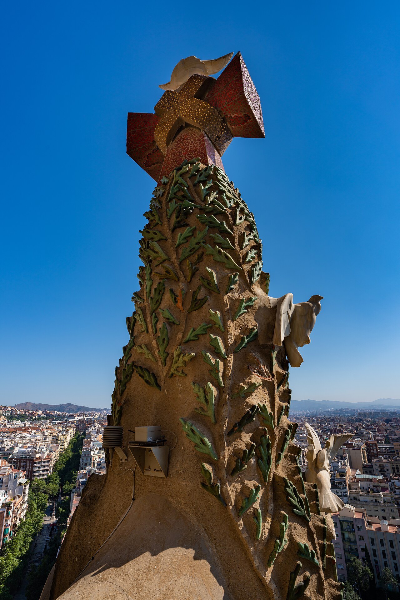 A carved stone spire of the Nativity façade, seen from the tower with the city far below.