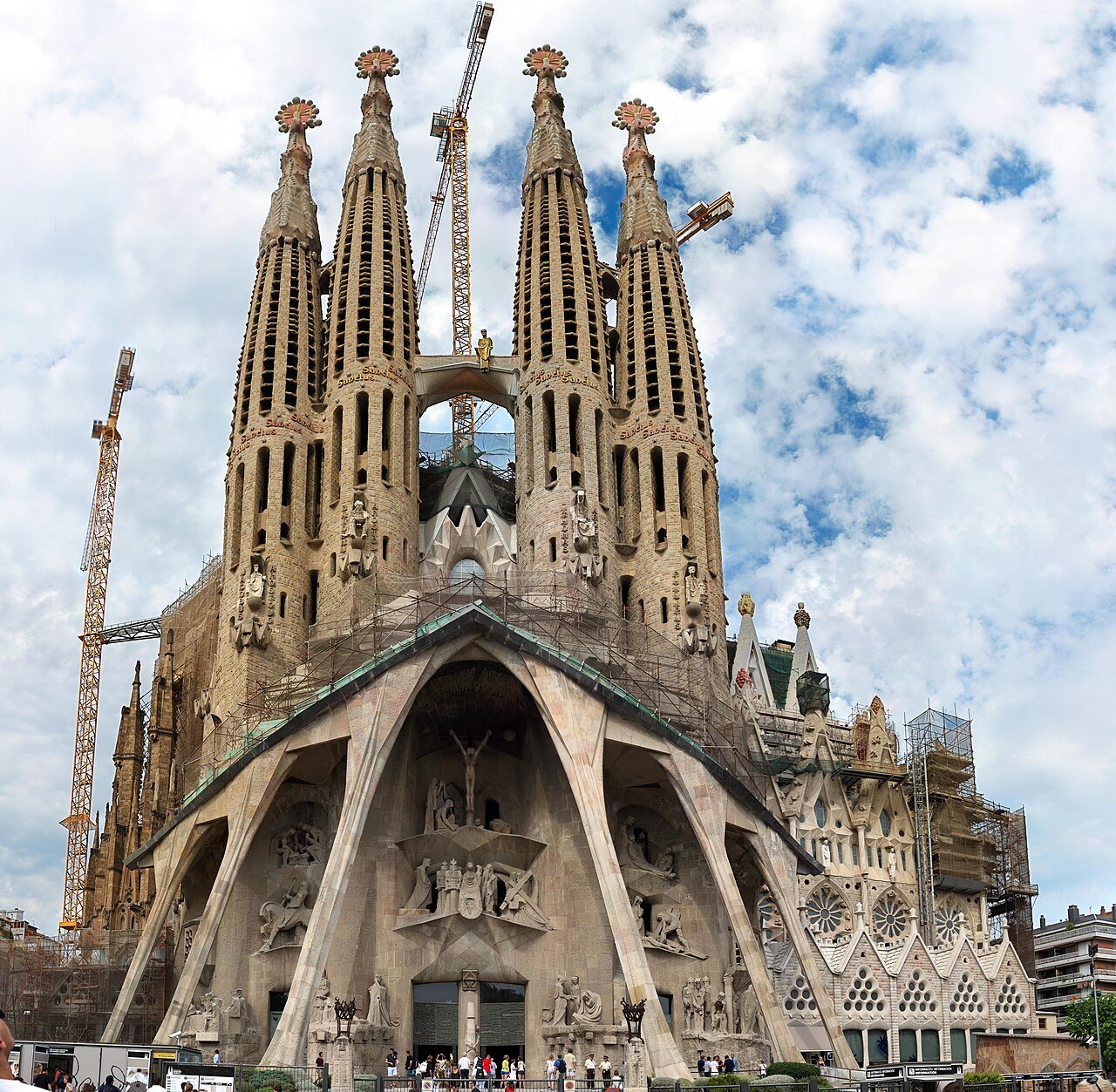 The Passion façade and its four spires rising against white clouds.