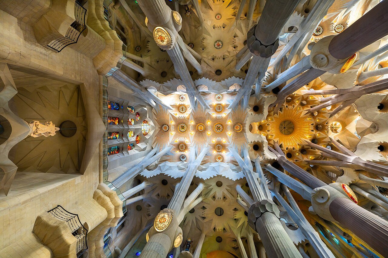 Looking up into the vaults of the Sagrada Família, where the columns branch like trees.