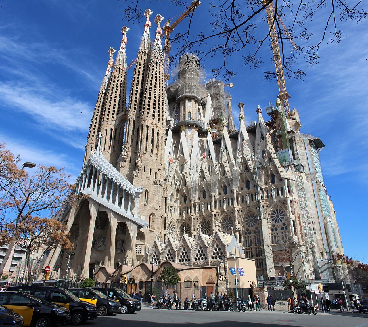 The basilica's towers seen from a street corner, with taxis parked along the curb.