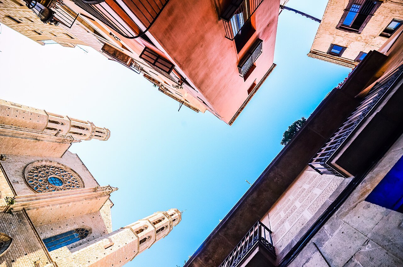 The rose window and tower of Santa Maria del Mar, seen looking up between the houses.