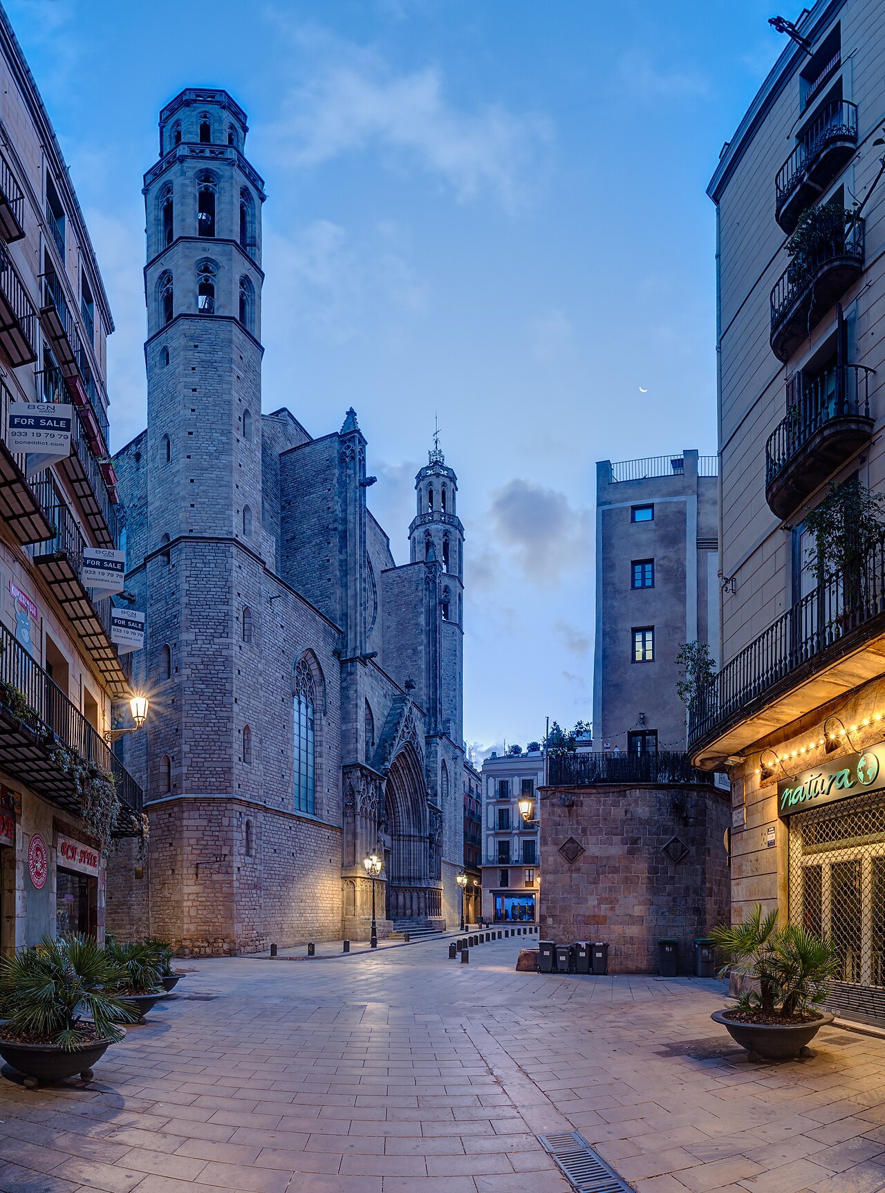 A quiet lane at dusk leading toward a Gothic church tower.