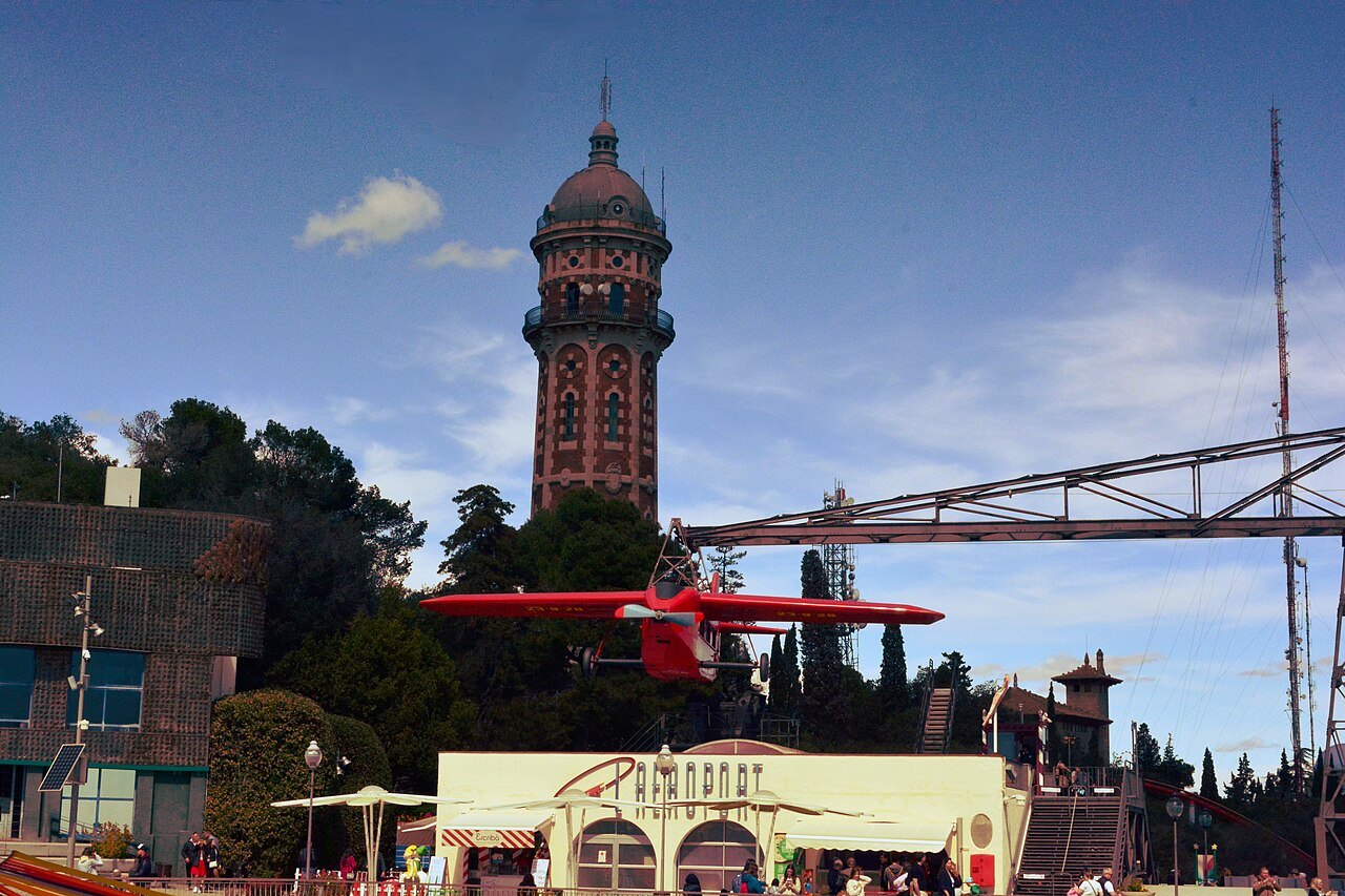A brick water tower and a red airplane ride at the Tibidabo amusement park.